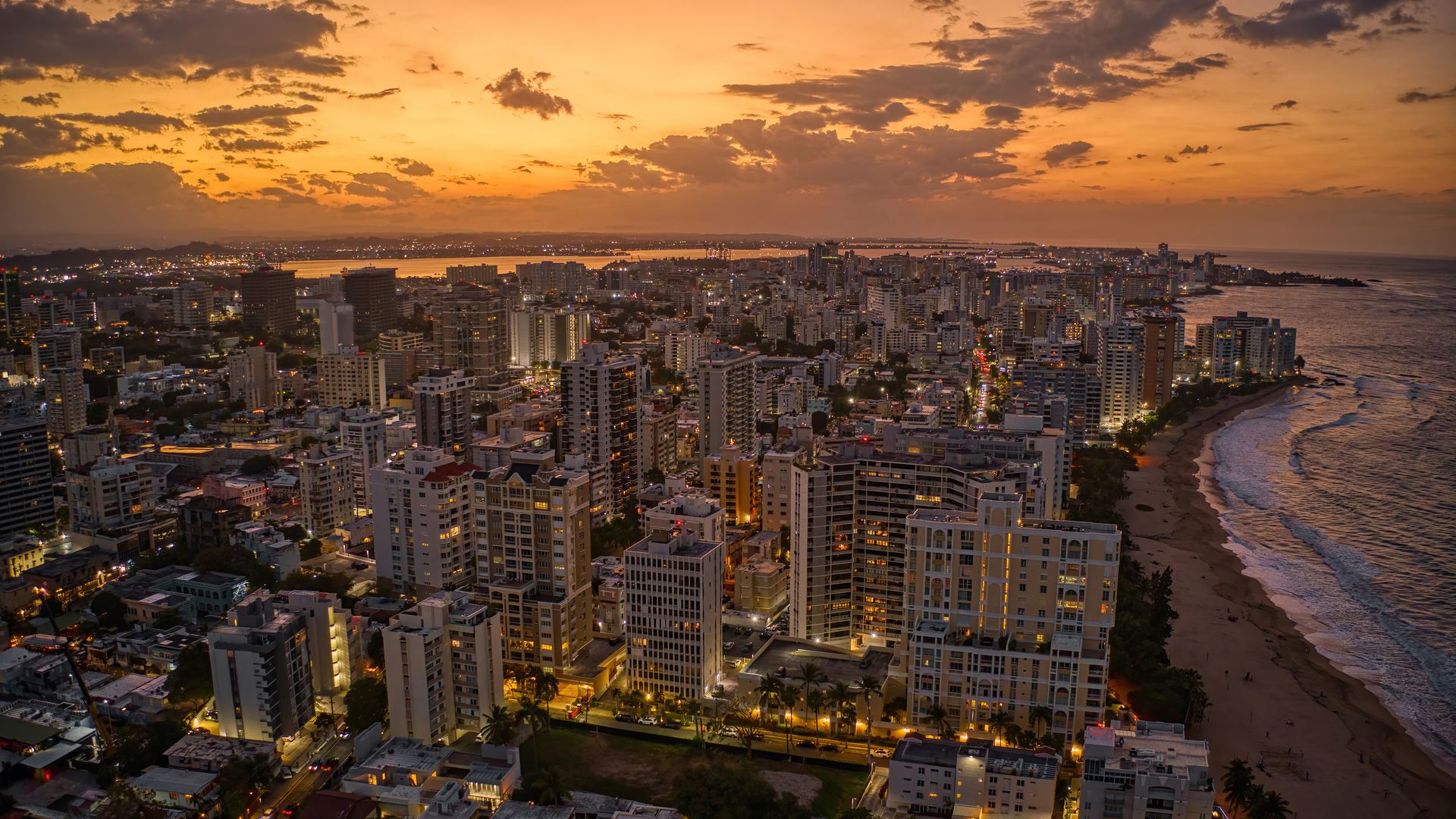 Vista aérea de Condado, en San Juan, al atardecer: edificios iluminados junto a la playa