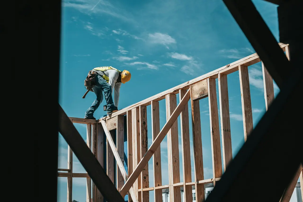 Carpenter working on timber framing against a blue sky