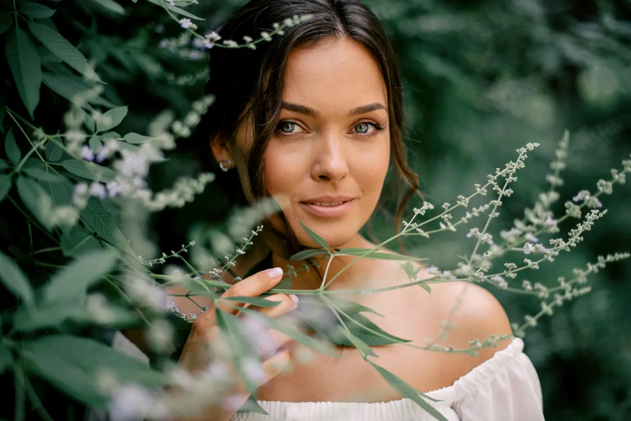 A woman with natural makeup among green foliage