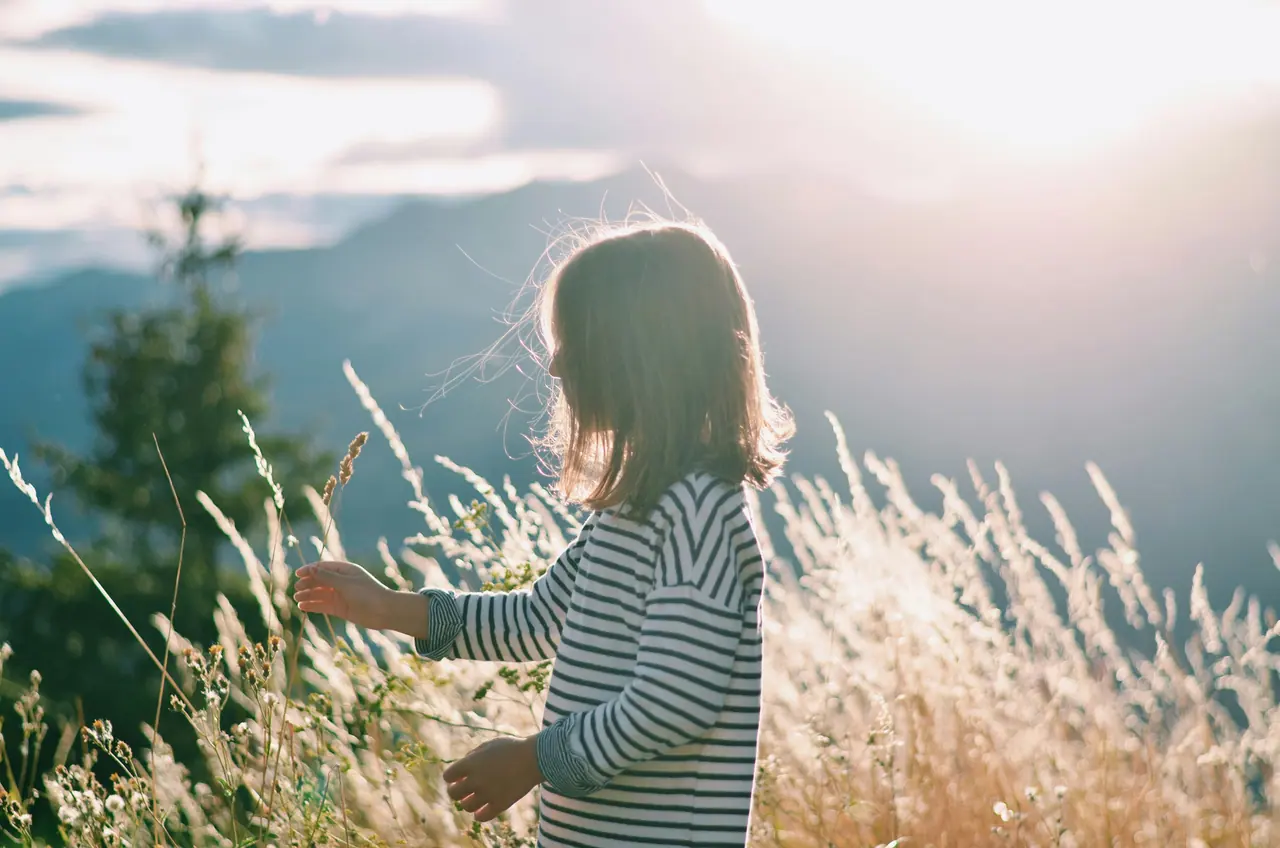 A young child exploring a sunlit meadow